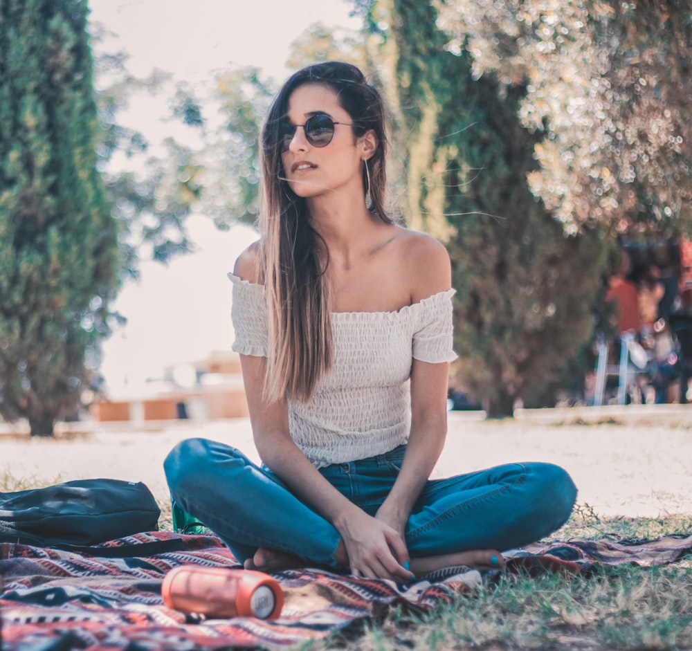 woman sitting on striped textile near tree at daytime