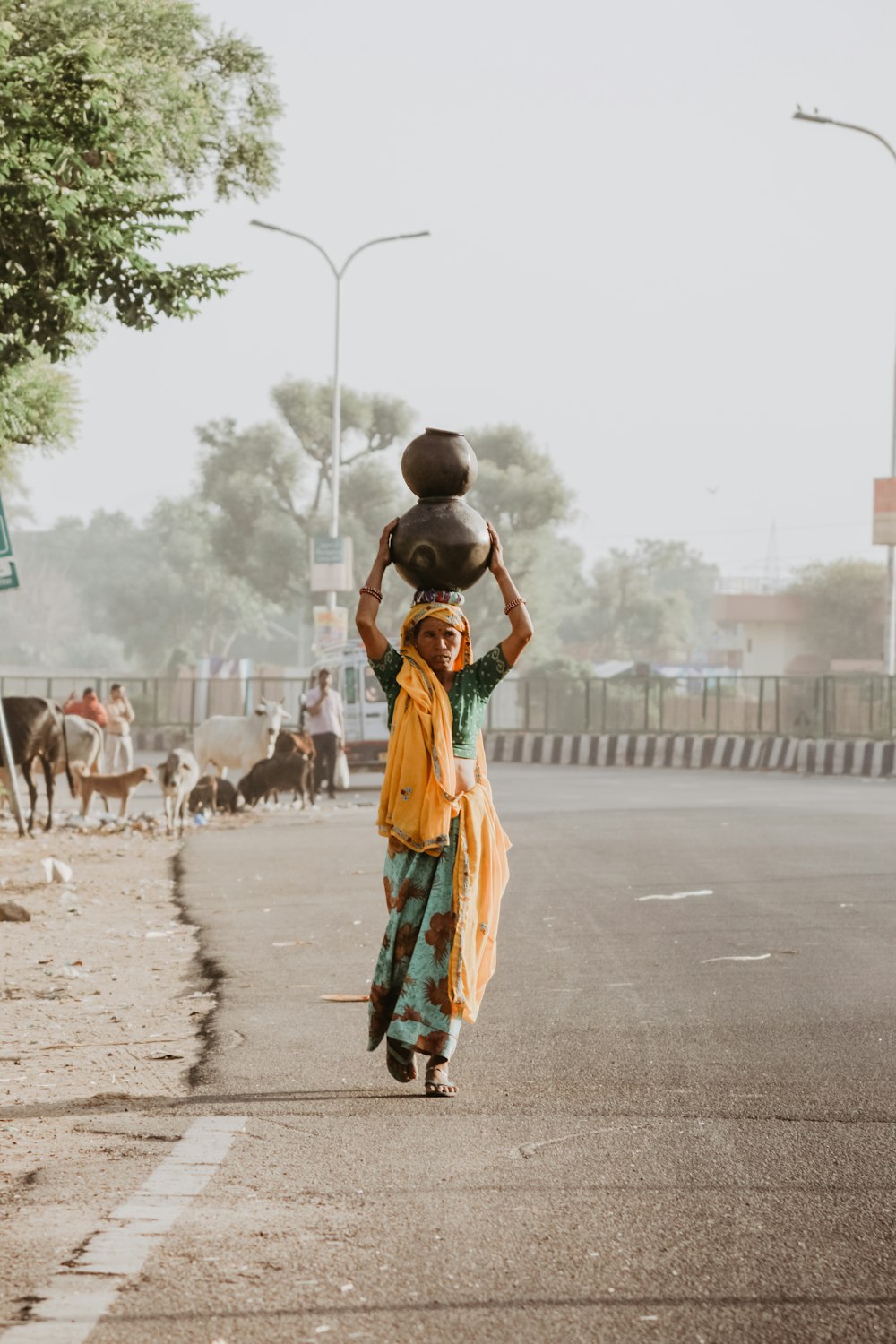 femme marchant sur la route portant deux jarres sur la tête