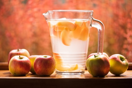 Refreshing apple drink in glass pitcher on wood table