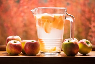 Refreshing apple drink in glass pitcher on wood table