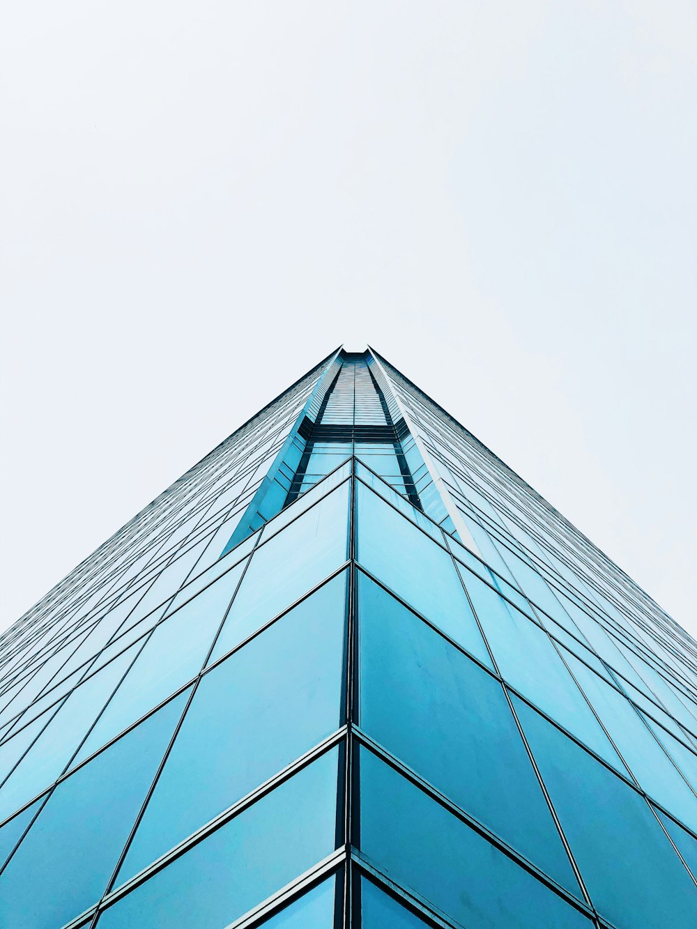 Un edificio di vetro molto alto con uno sfondo del cielo