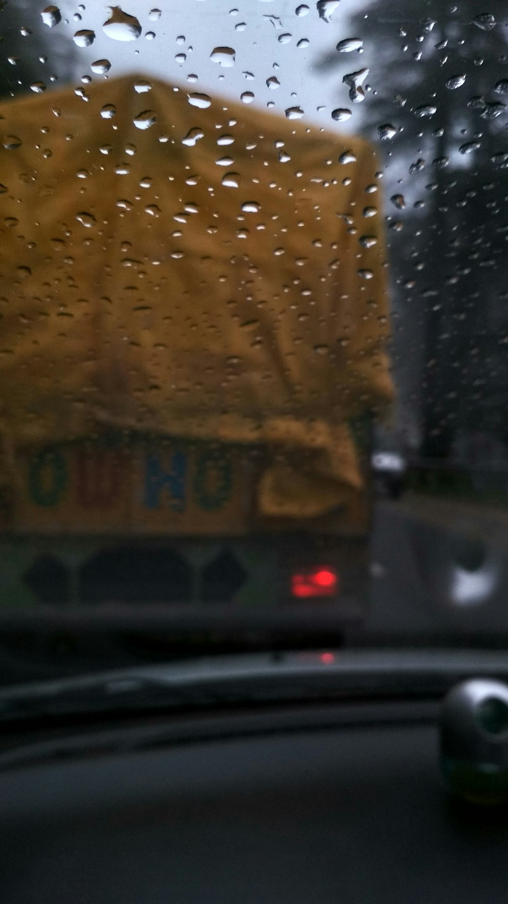 a rain covered bus is seen through a windshield