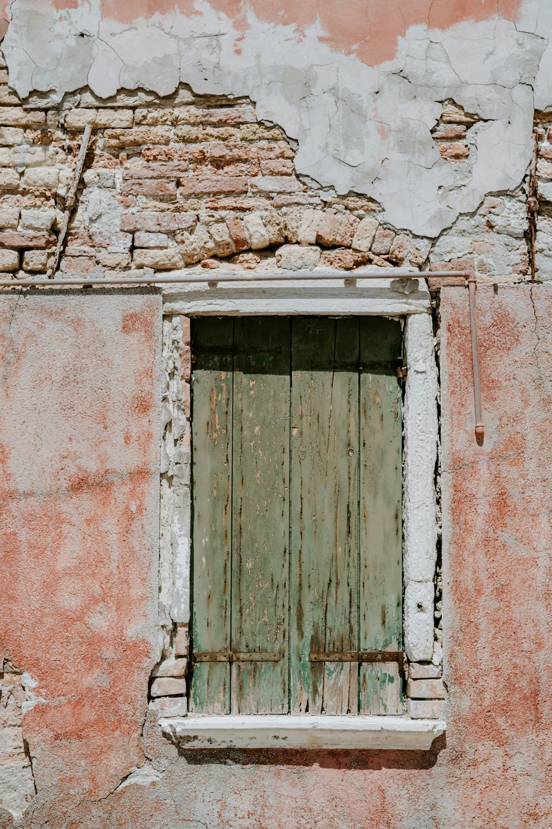 Window with shutters on textured weathered wall
