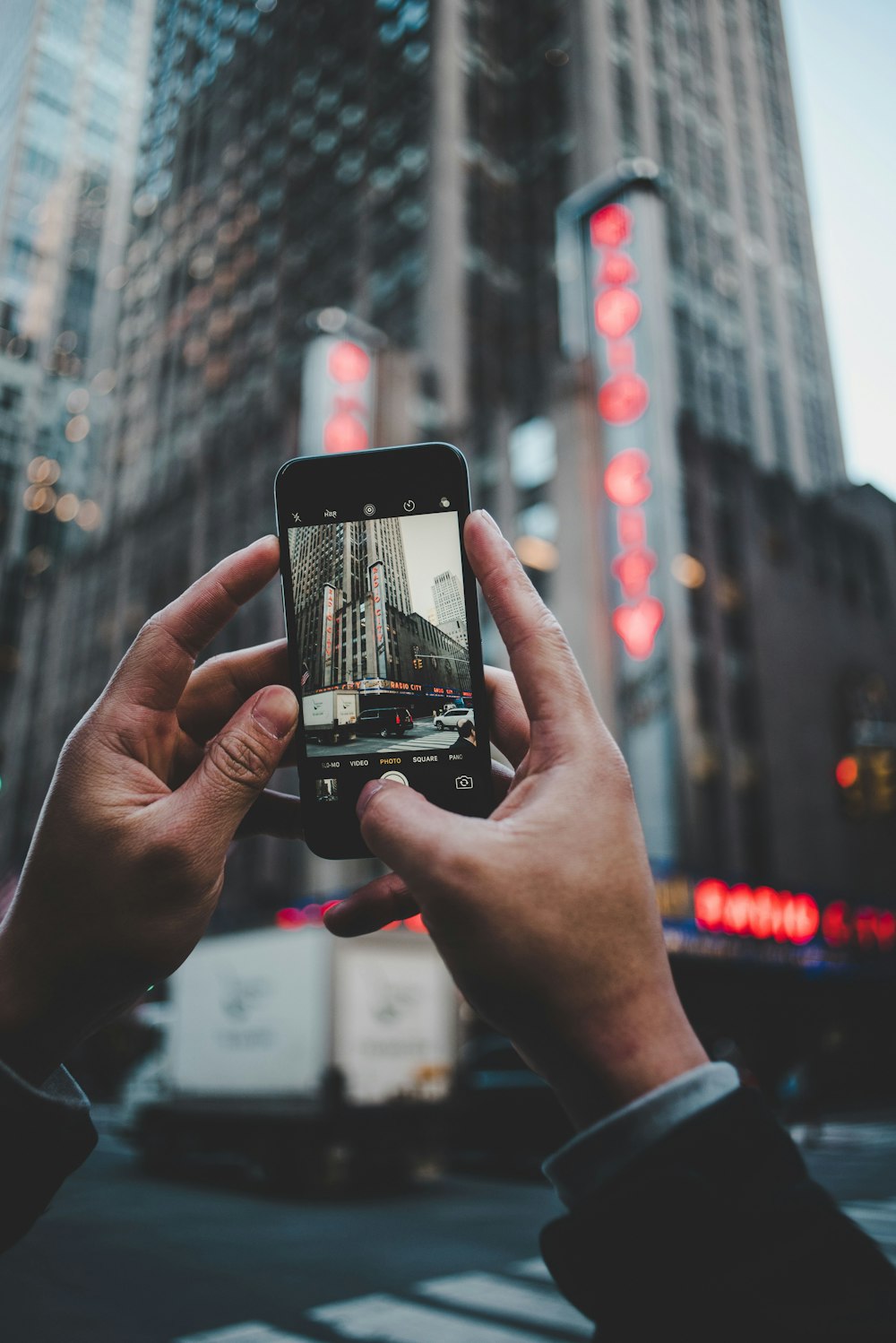 person capturing high-rise building during daytime