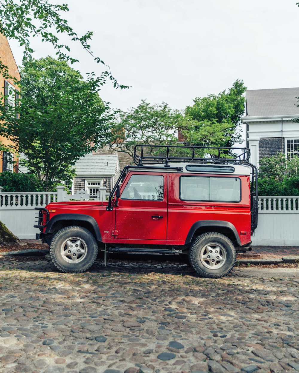 red off-road car parked at sidewalk