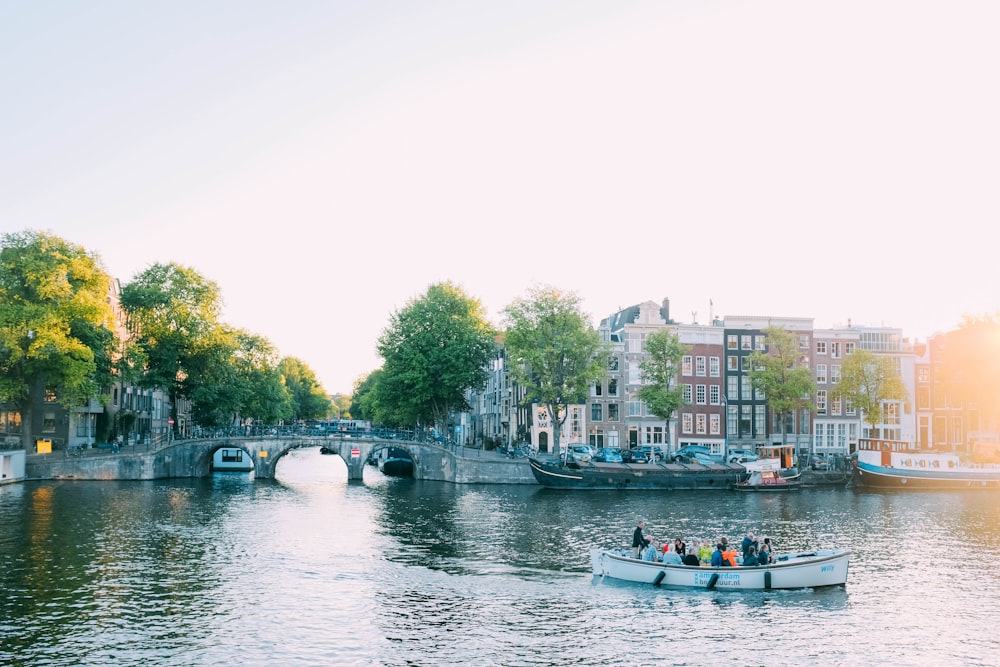 people riding canoe beside concrete bridge at daytime