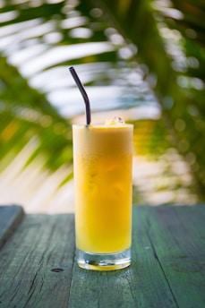 clear drinking glass filled with yellow liquid on brown table