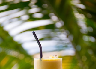 clear drinking glass filled with yellow liquid on brown table