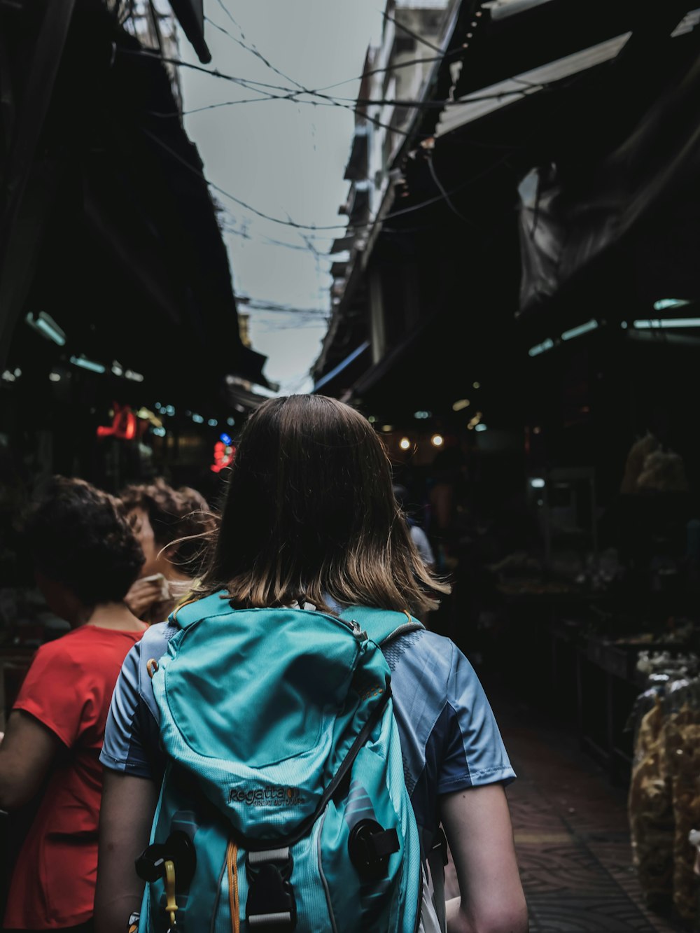 person wearing blue backpack walking beside person in red shirt