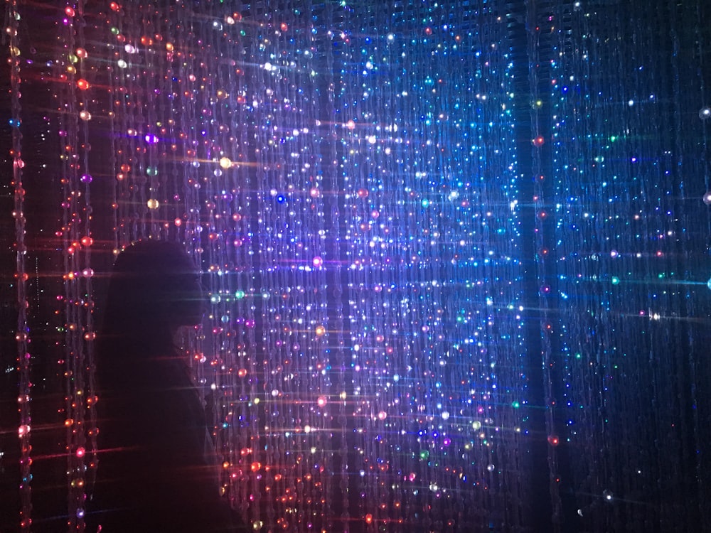 person standing in front of beaded lighted curtains