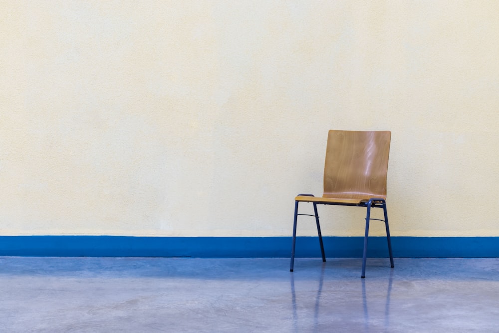 sedia di legno marrone accanto alla parete bianca