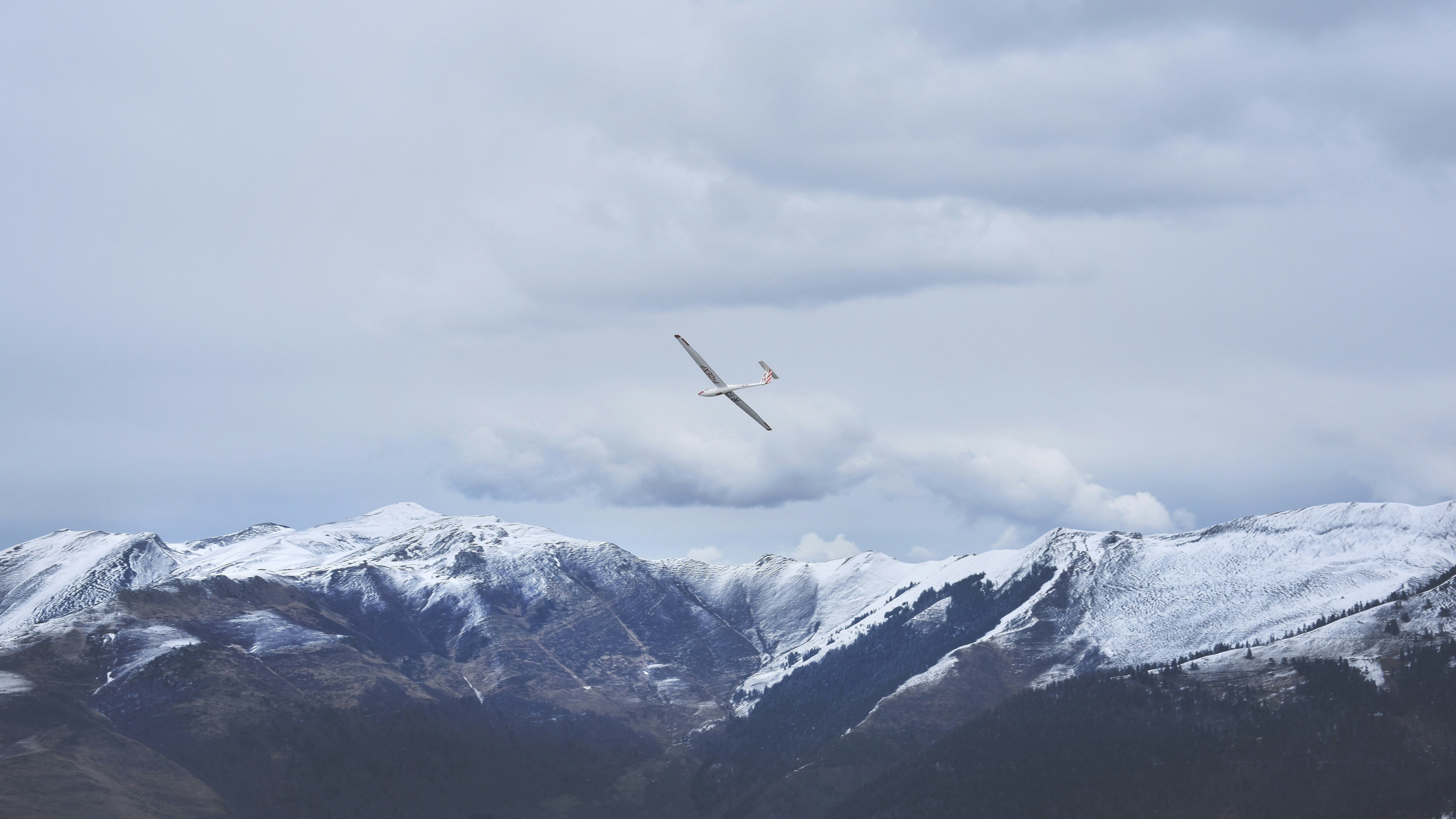 white airplane on sky, We went to Luchon, a beautiful small town in south of France, for skiing trip. We stayed in a hotel on top of the snow covered hill. It was a weekend and it snowed heavily in the night. The next morning we saw so many gliders in the sky hovering over the snowy peaks. It was an awesome experience to watch these gliding silently.