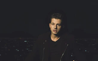 A moody, cinematic shot of a young person wearing époque noire streetwear against an urban night backdrop.