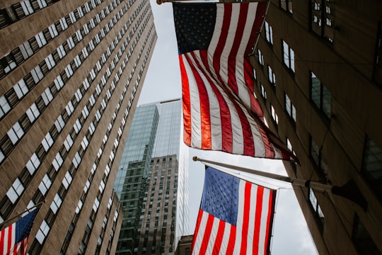 worm's eye view photography of USA flag on pole in Rockefeller Center United States
