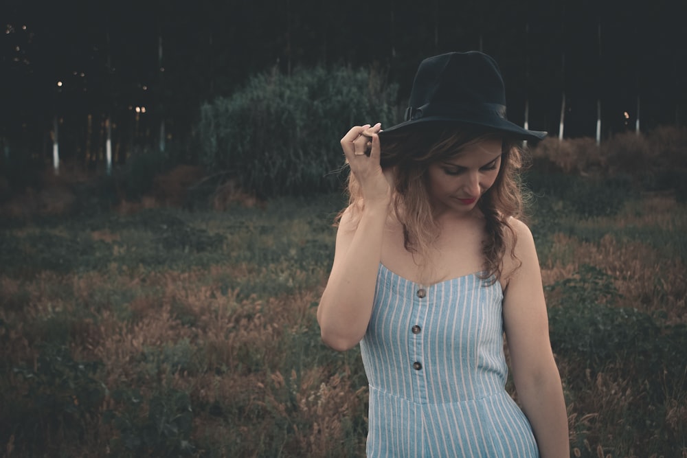 woman holding her hat while looking down