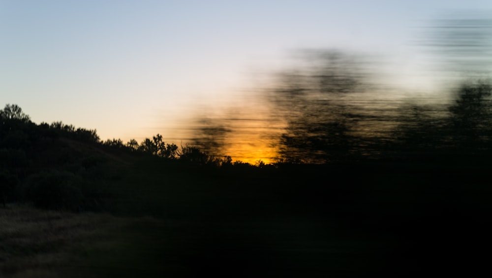 a blurry photo of a sunset with trees in the foreground