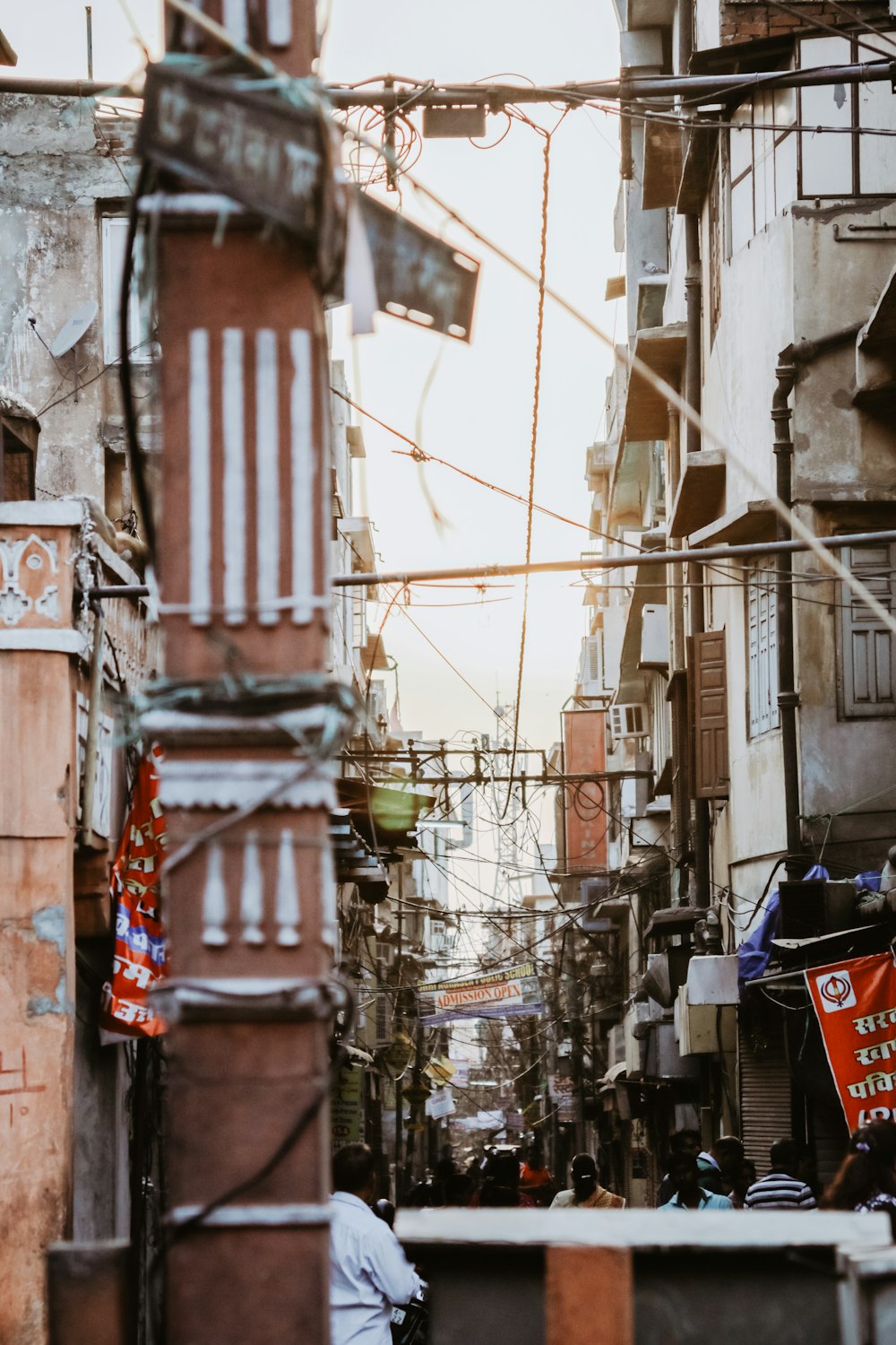 people in alley in middle of buildings under cables