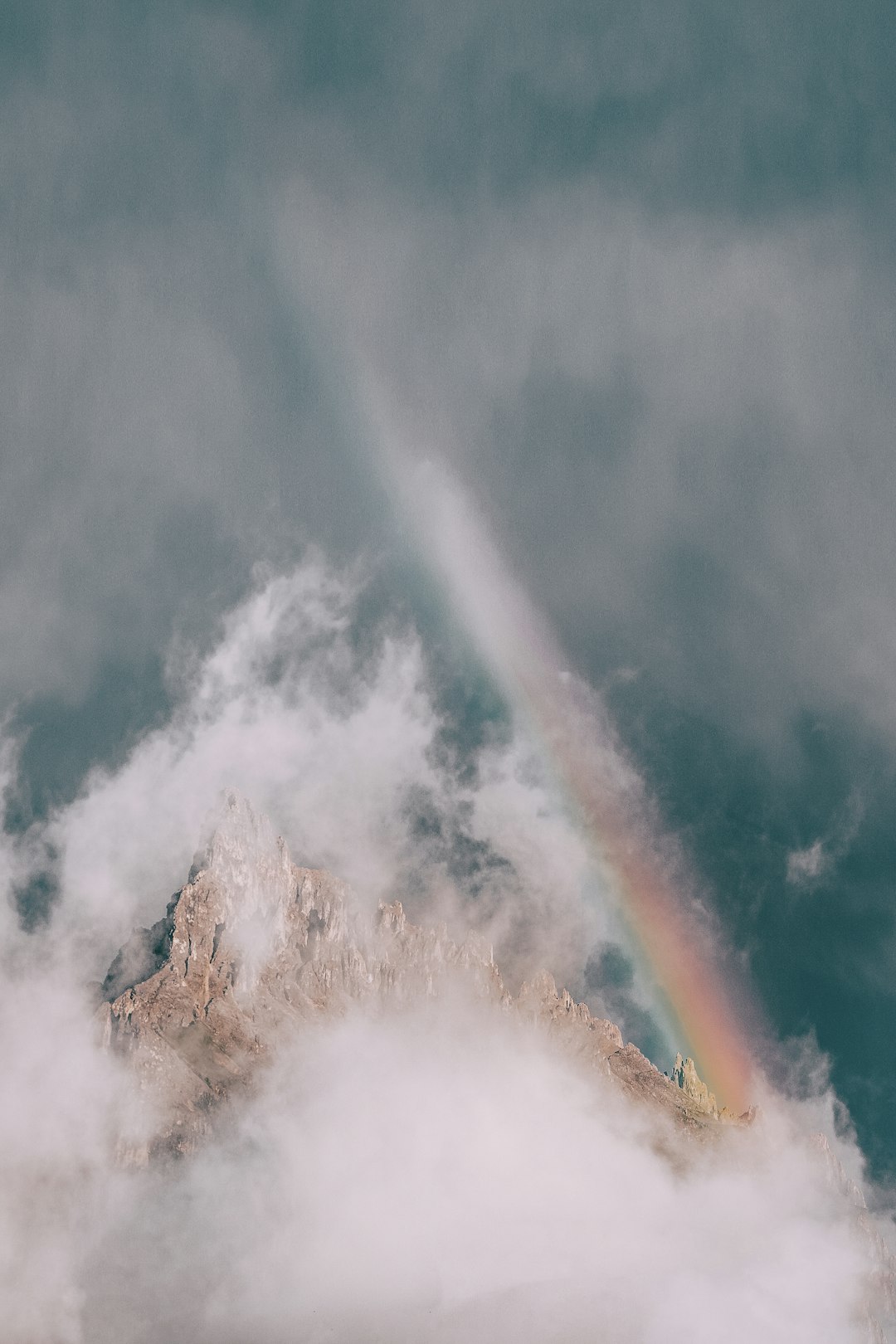 rock mountain covered in fog with rainbow