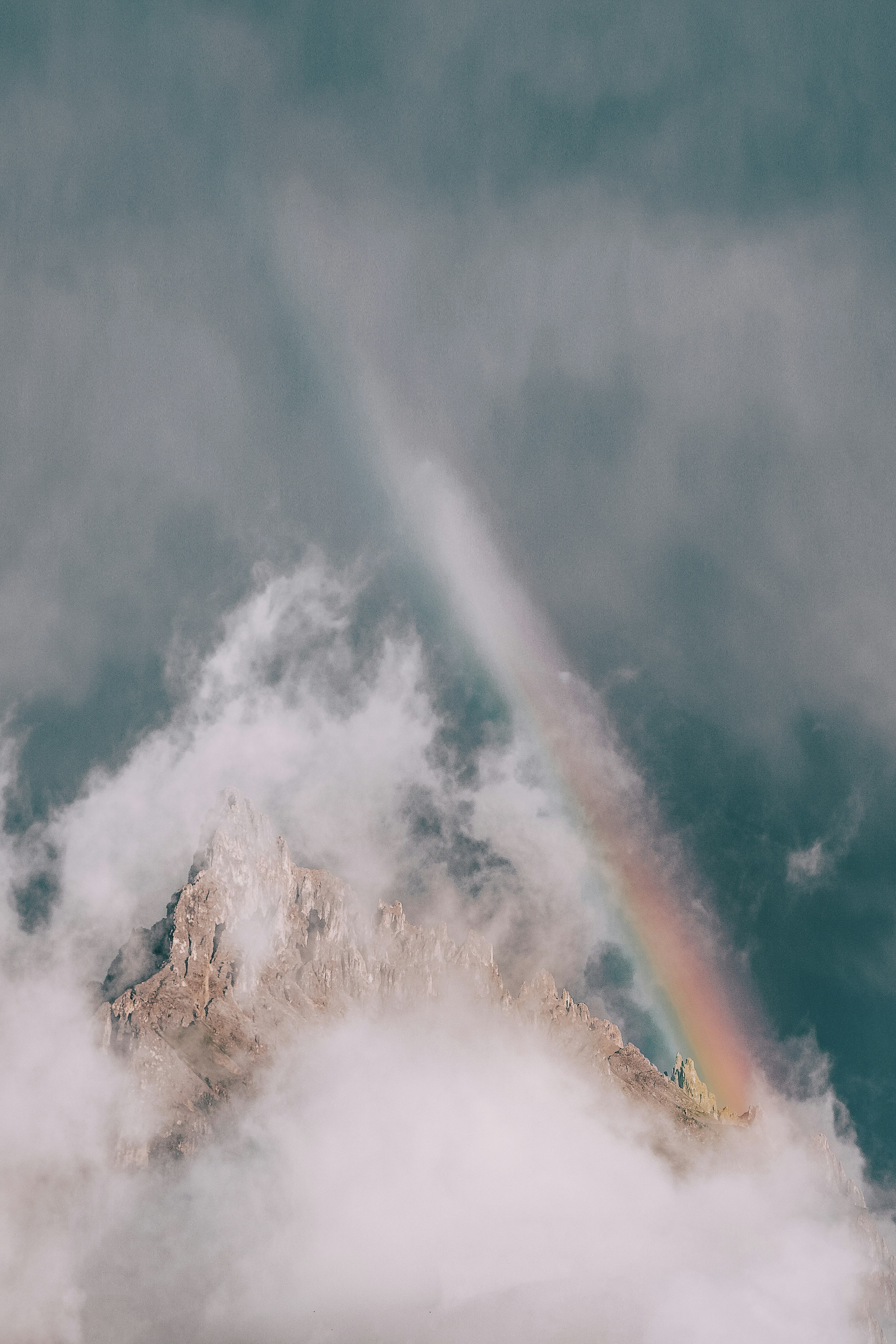 rock mountain covered in fog with rainbow