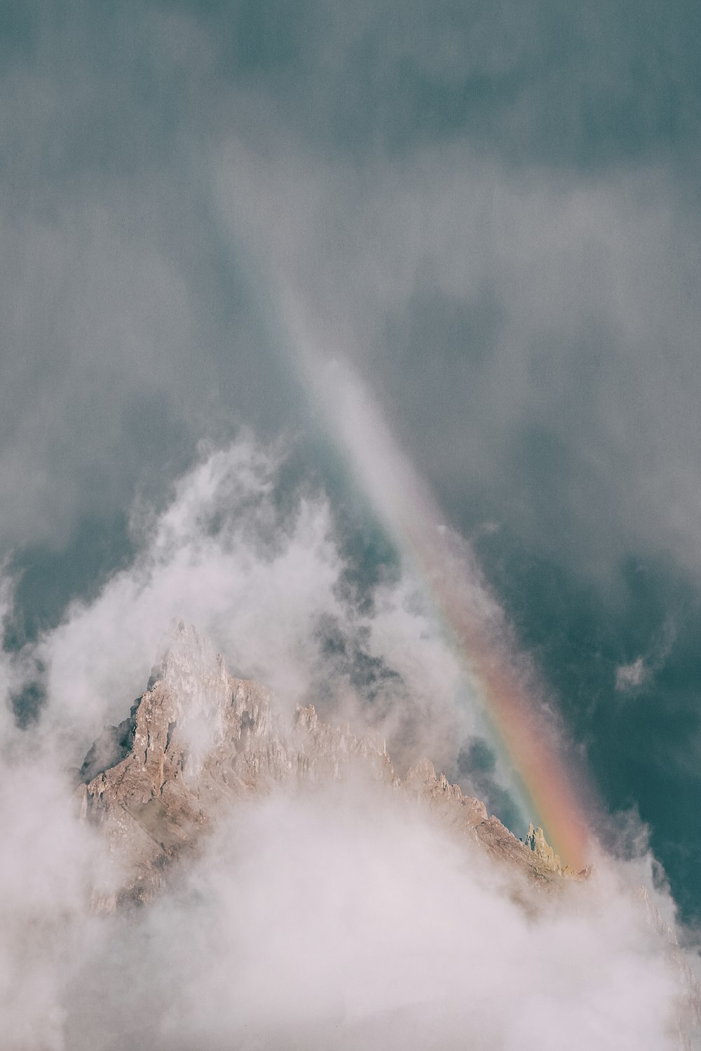 Montanha de rocha coberta de nevoeiro com arco-íris