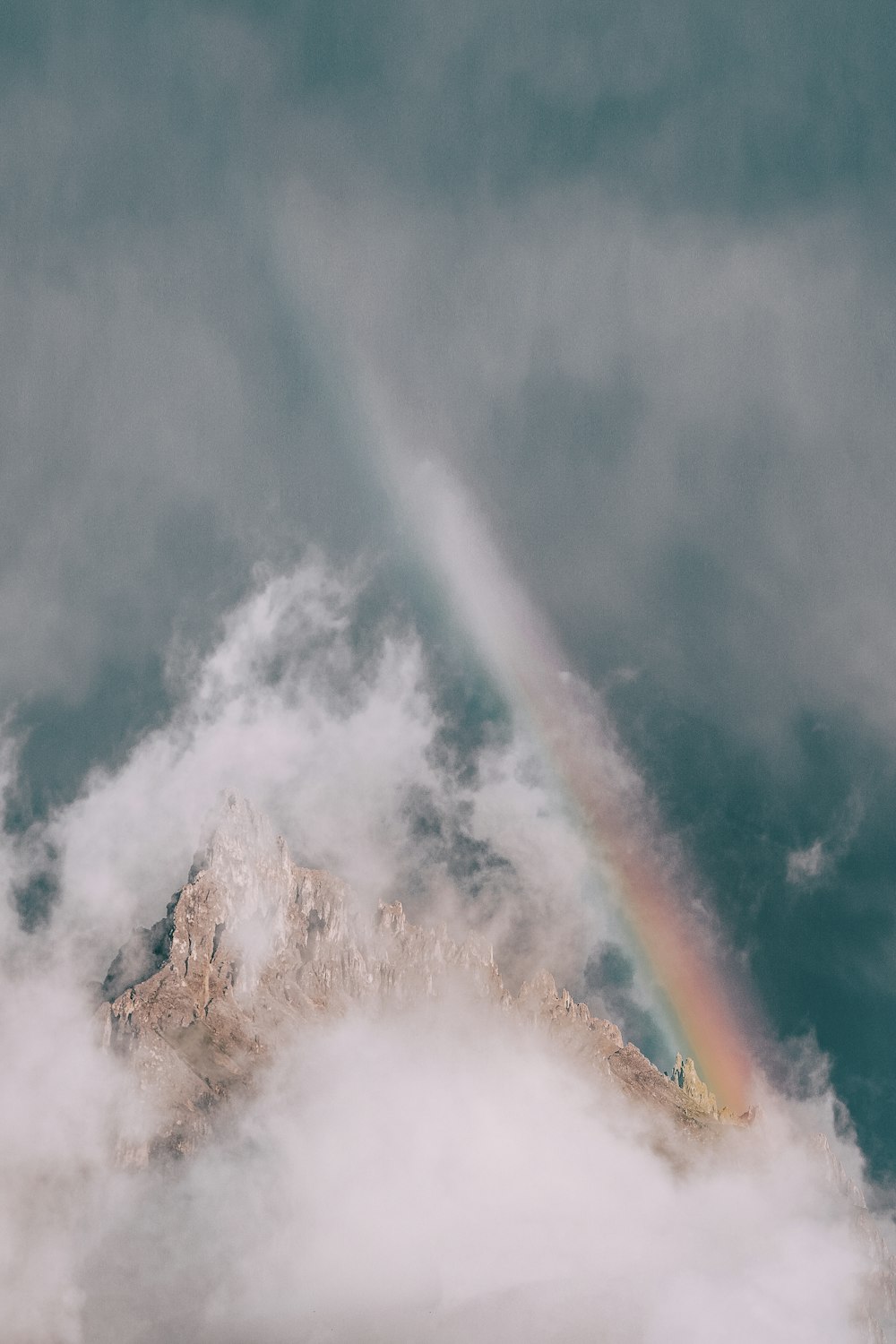 montagne rocheuse couverte de brouillard avec arc-en-ciel