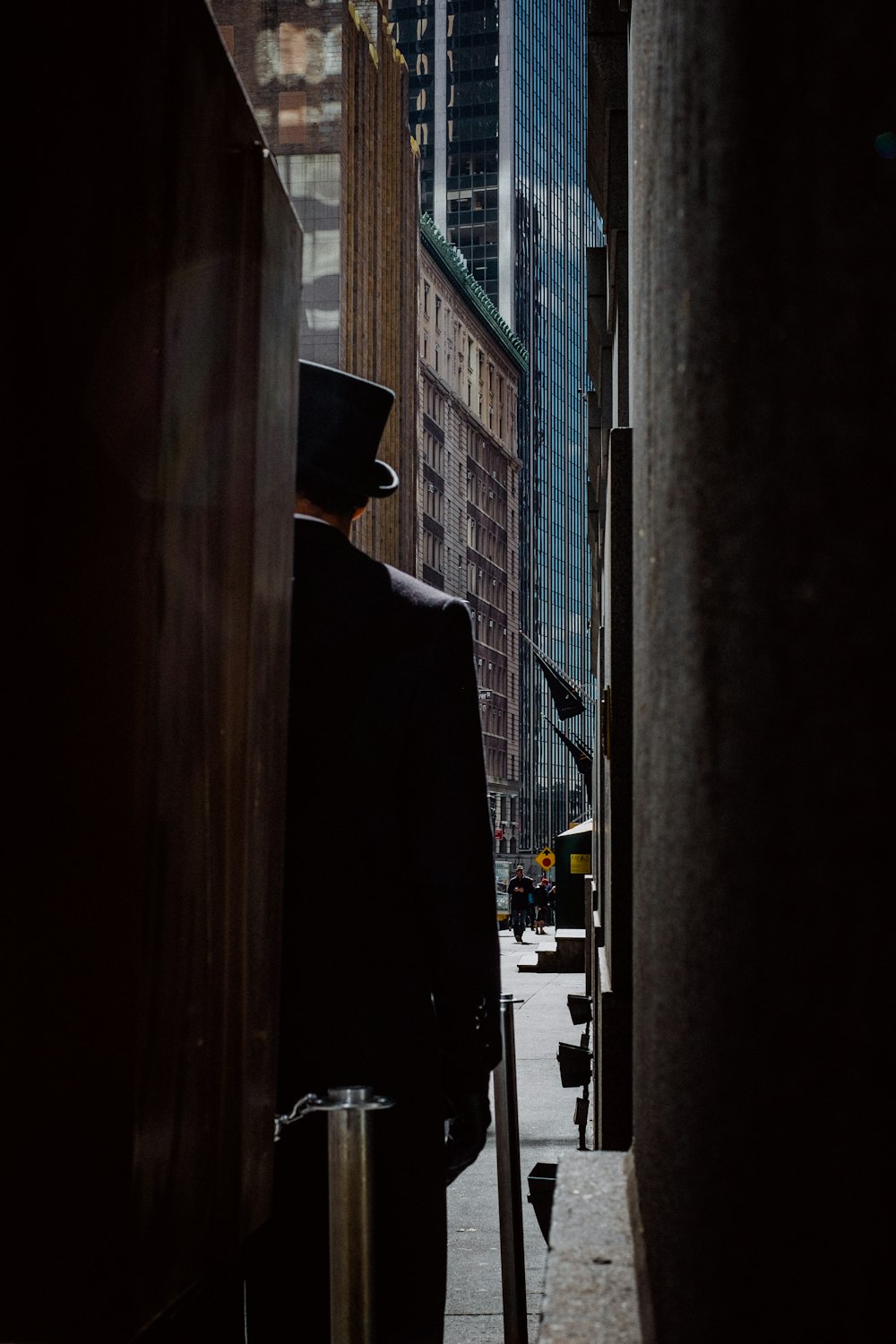 uomo che indossa il cappello a cilindro in piedi vicino agli edifici