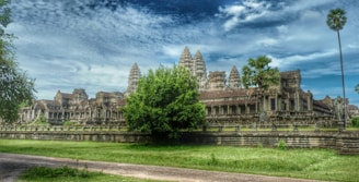 An aerial shot of an Indian temple complex surrounded by lush greenery under a clear sky.