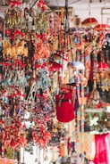A vibrant display of colorful hanging decorations including embroidered cloth elephants, umbrellas, and bags. These items are intricately designed with a myriad of hues, showcasing traditional artistry and craftsmanship with beads and tassels adding to the decorative appeal.