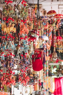 A vibrant display of colorful hanging decorations including embroidered cloth elephants, umbrellas, and bags. These items are intricately designed with a myriad of hues, showcasing traditional artistry and craftsmanship with beads and tassels adding to the decorative appeal.