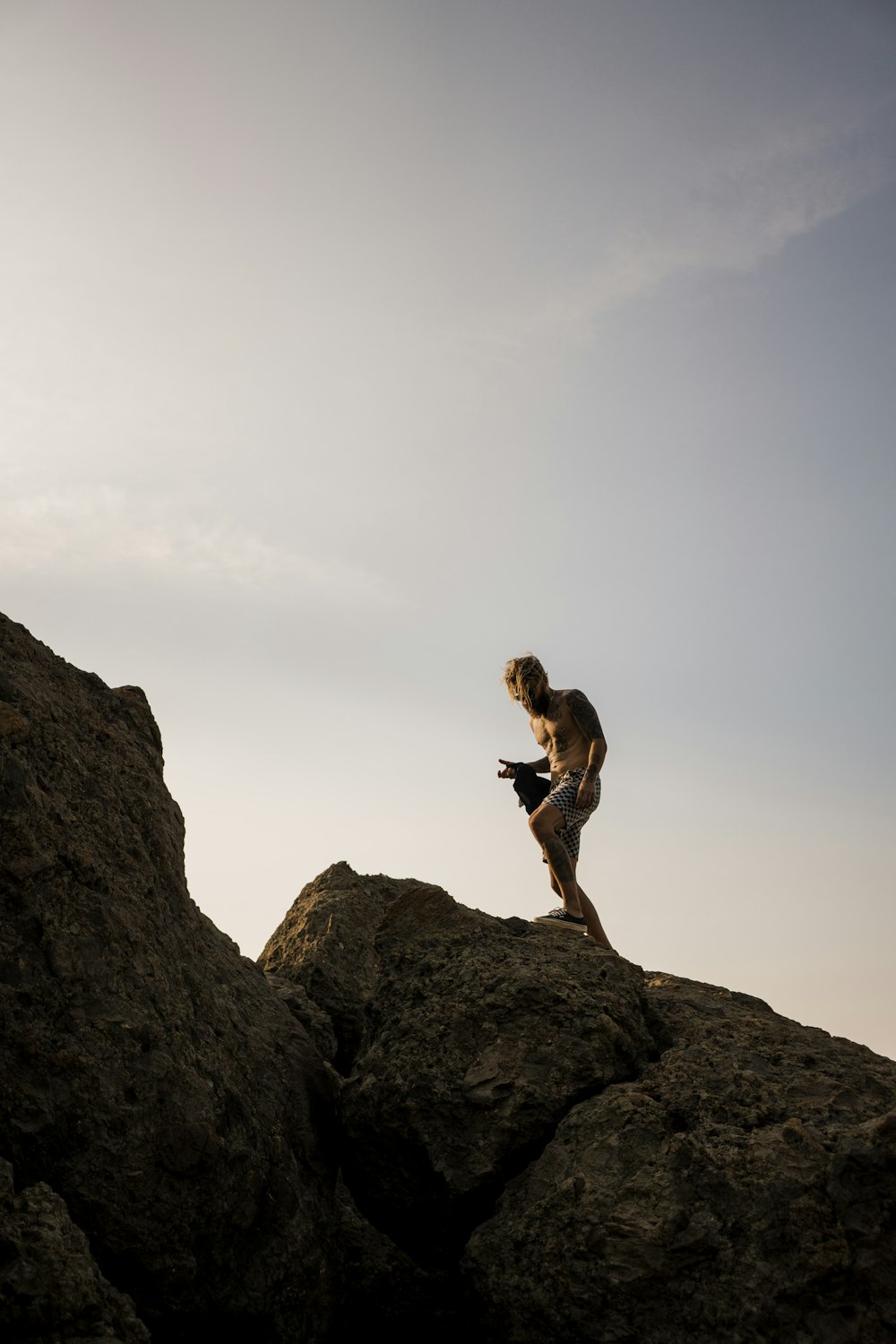 man wearing white shorts standing on brown rocks under clear blue sky