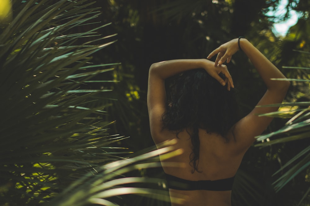 woman raising arms between trees