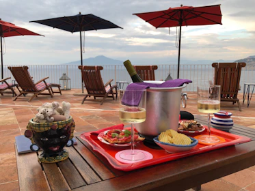 A rustic table set with Mediterranean tapas and bottles of local wine, framed by the sea horizon.