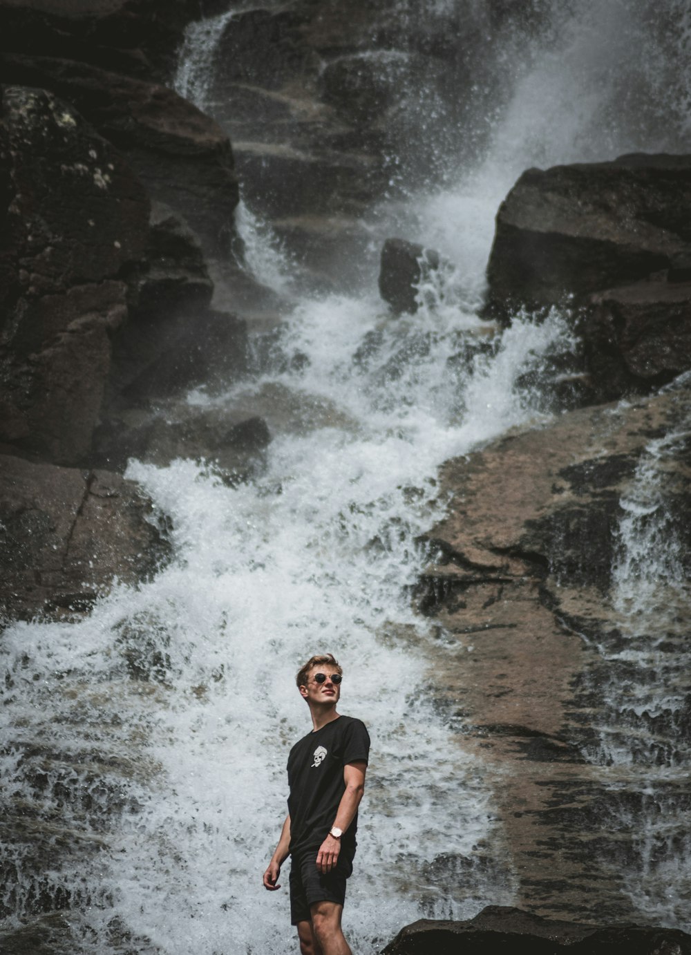 homem em pé na frente de cachoeiras