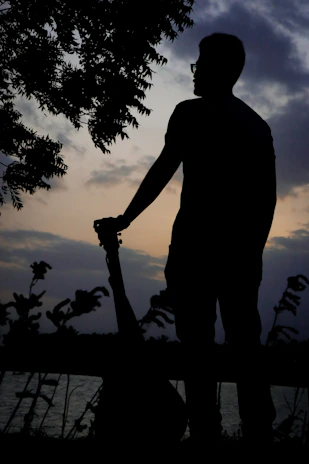 A serene portrait of a singer-songwriter with an acoustic guitar outdoors.