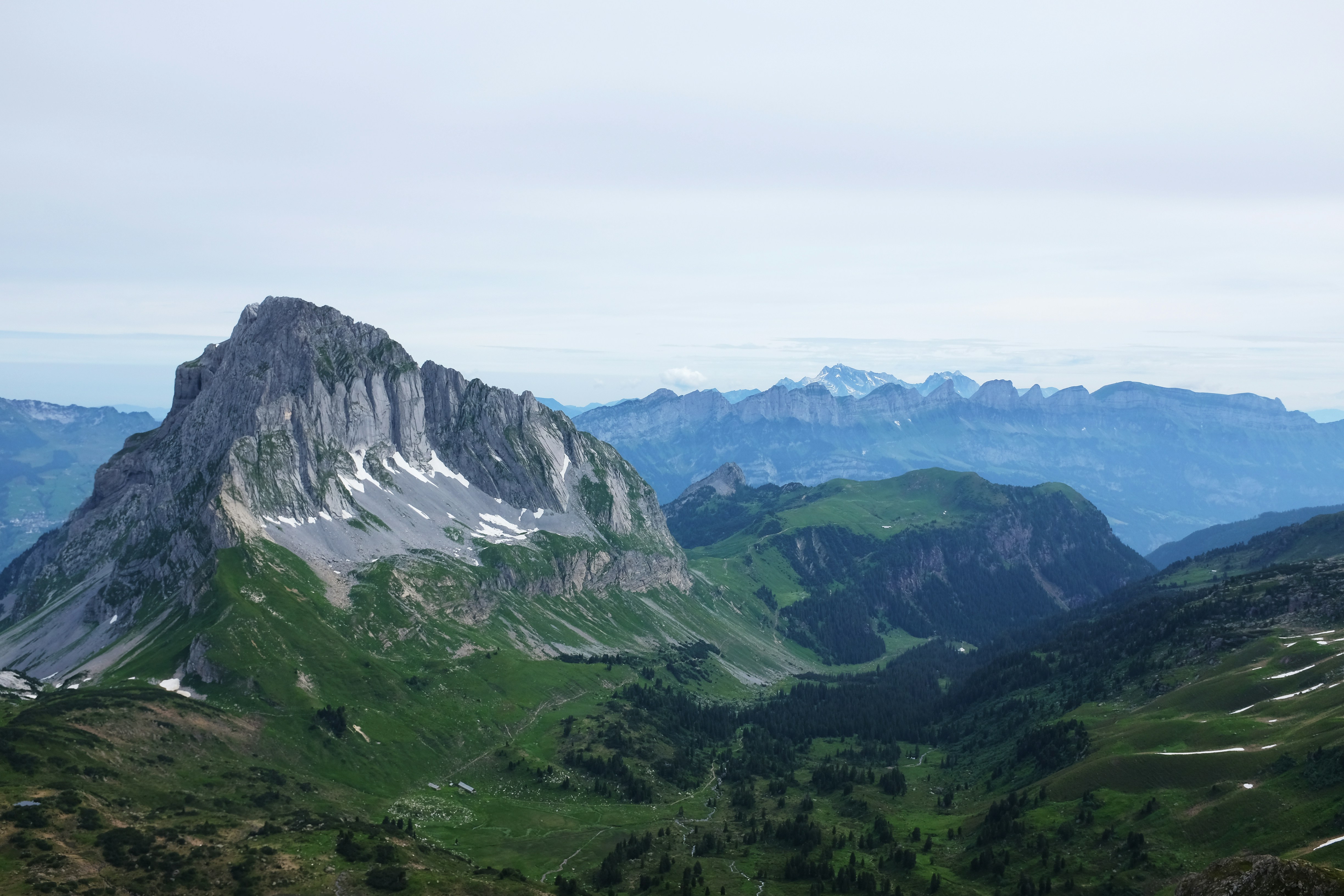 person taking photo of mountain under blue and white sky at daytime