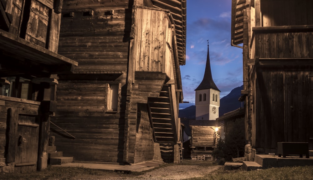 brown wooden house near white clock tower at nighttime