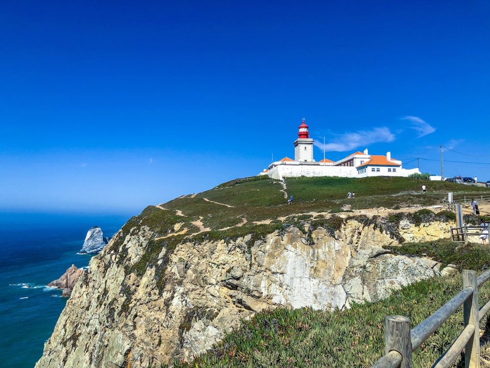 lighthouse on mountain near body of water