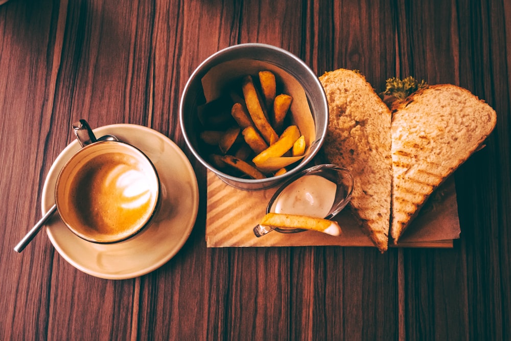 French fries in bucket near sandwich on plate on table