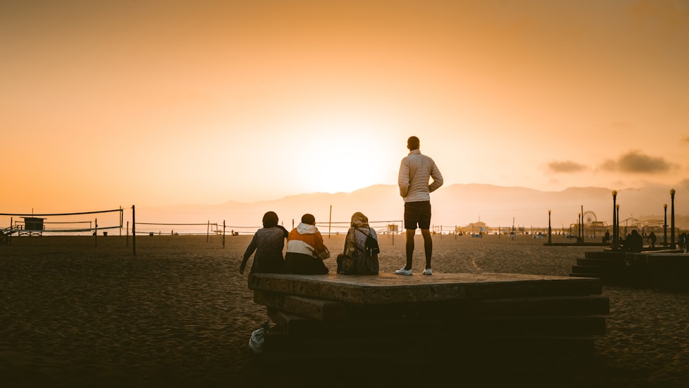 three person sitting on ground beside man