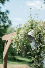 Rustic arch adorned with wildflowers and flowing fabric at an outdoor wedding.