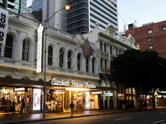 man standing beside Elizabeth Picture Theater building in The Elizabeth Picture Theatre Australia