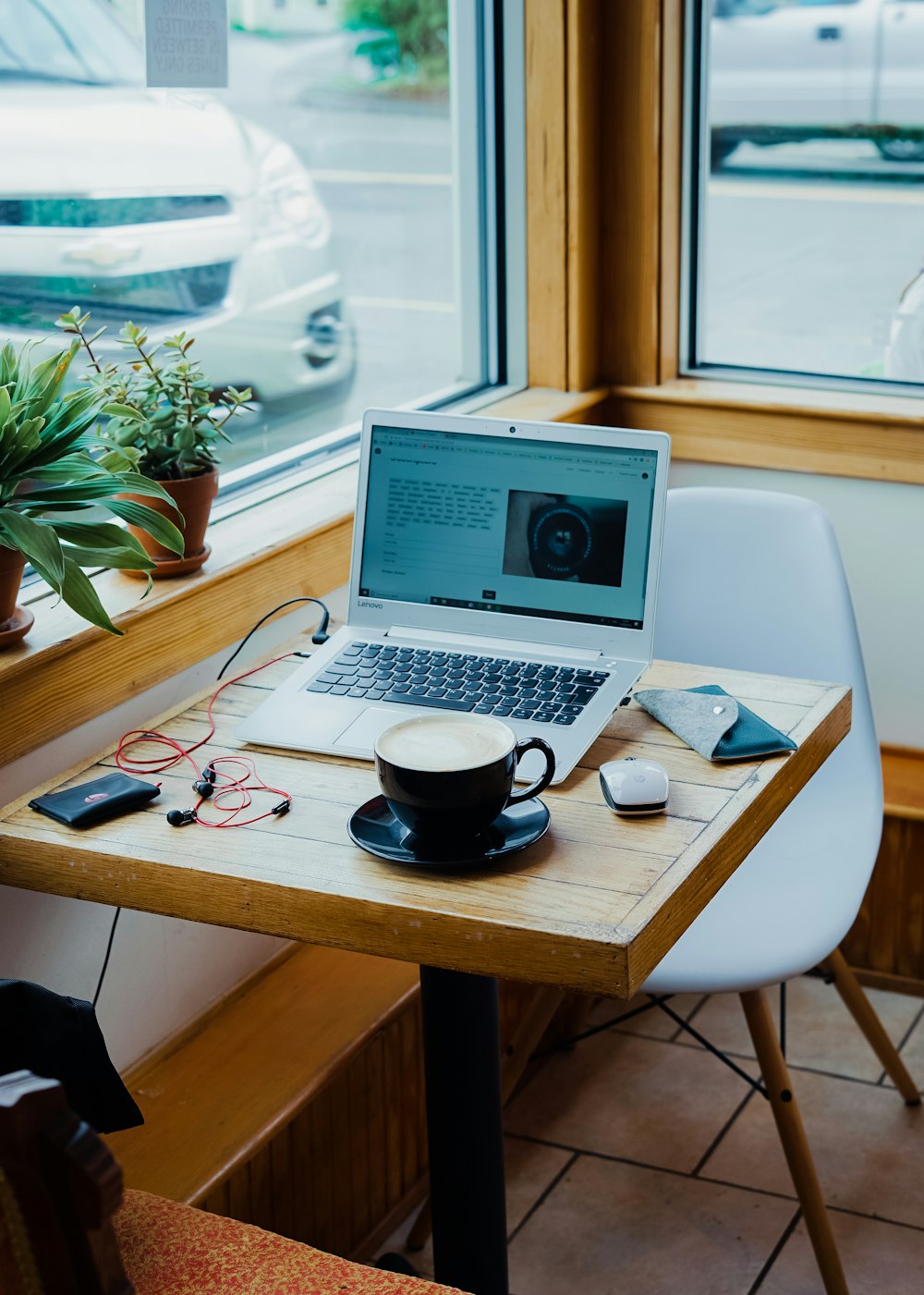 Tasse Kaffee, Laptop und rote Kopfhörer eingesteckter Laptop auf braunem Holztisch