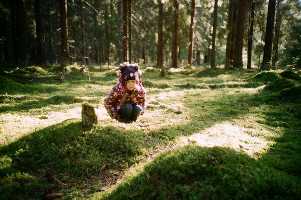 girl sitting in the middle of green woods