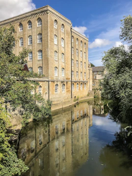 brown concrete building near grey body of water and trees at daytime