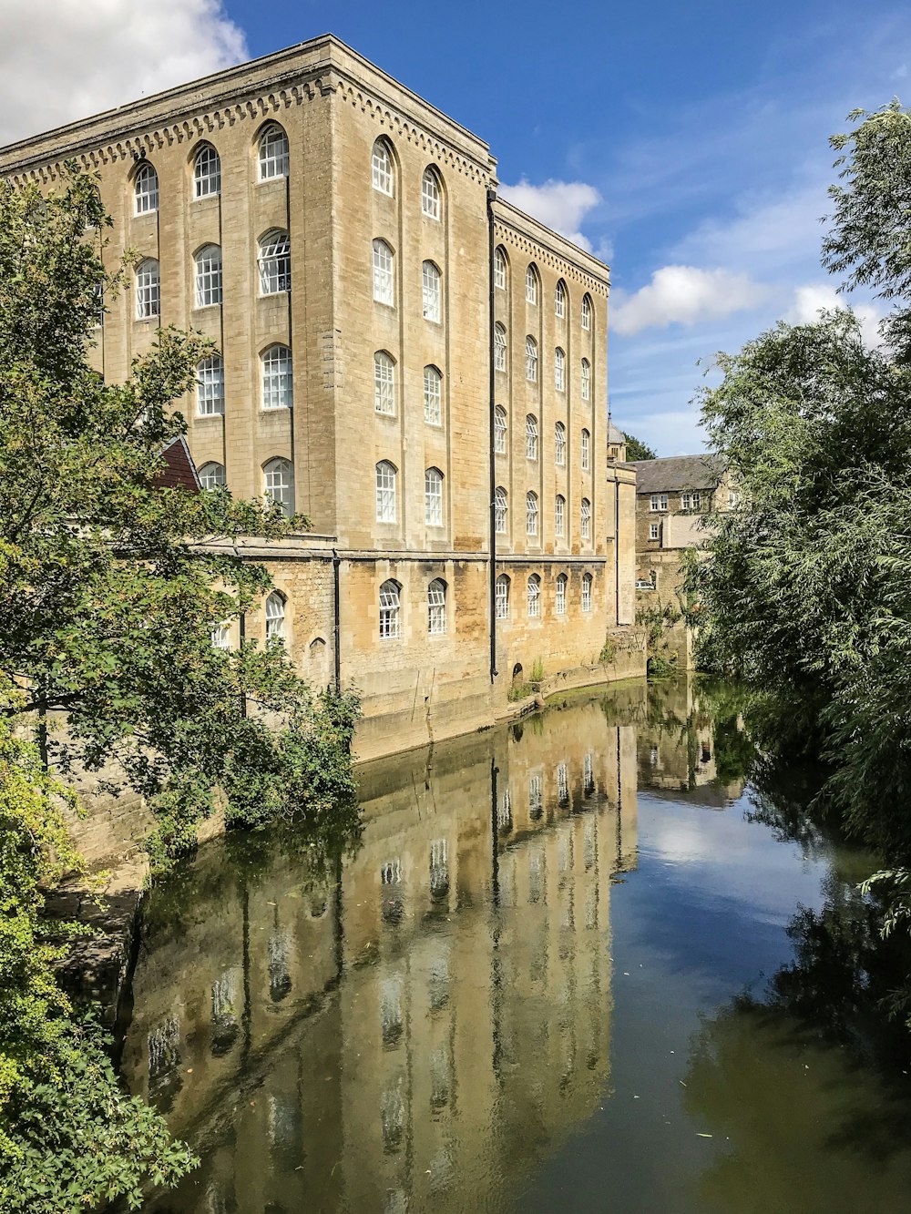 edificio in cemento marrone vicino allo specchio d'acqua grigio e agli alberi durante il giorno