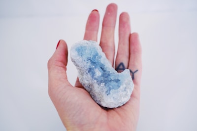a person's hand holding a small piece of ice