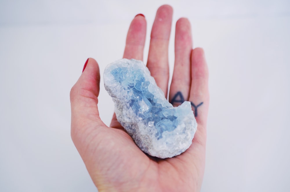 a person's hand holding a small piece of ice