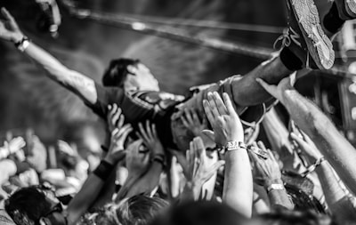 A fan wearing a Coreforge tee, crowd surfing at a packed metalcore concert.