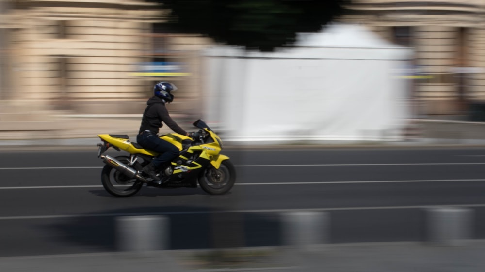日中に黄色いスポーツバイクに乗っている男性の浅い焦点の写真