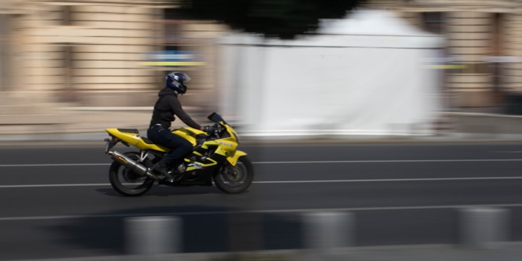 shallow focus photo of man riding on yellow sport bike during daytime